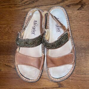 Alegria
by PG Lite brown leather Velcro strap sandals with bronze details on top
